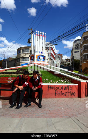 Gli studenti seduti su una panchina accanto a un monumento ebraico che è stata sfigurata in segno di protesta contro le azioni di Israele nella Striscia di Gaza, La Paz, Bolivia Foto Stock