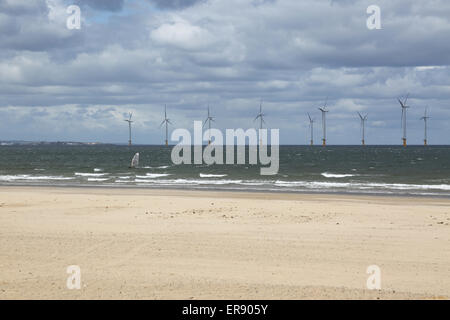 Un windsurf passa il Teeside wind farm fotografata da Redcar beach. 27 turbine offshore nell'estuario del fiume Tee Foto Stock