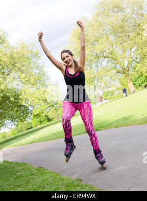 Felice giovane donna con pattini nel parco Foto Stock