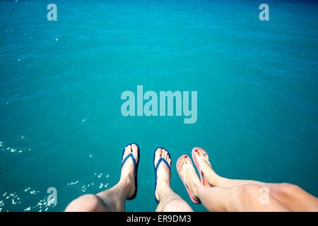 Coppia di gambe in pantofole sullo sfondo del mare Foto Stock