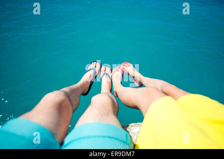 Coppia di gambe in pantofole sullo sfondo del mare Foto Stock