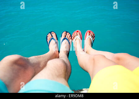 Coppia di gambe in pantofole sullo sfondo del mare Foto Stock