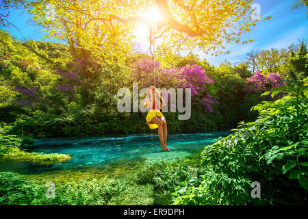 Donna oscillare sul fiume Foto Stock