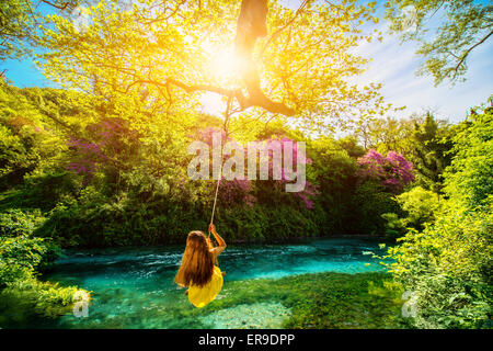 Donna oscillare sul fiume Foto Stock