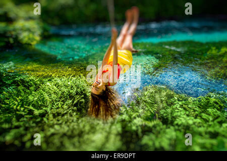 Donna oscillare sul fiume Foto Stock