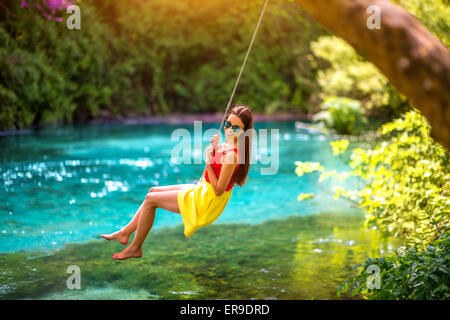 Donna oscillare sul fiume Foto Stock