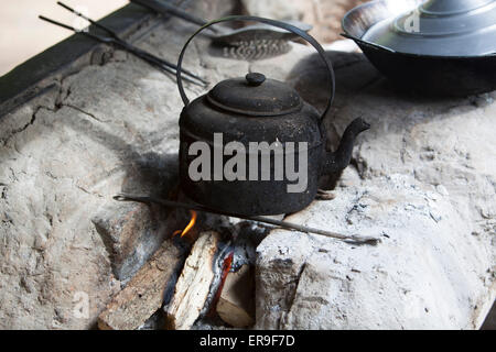 Una fumata nera, bollitore, impostato su legno che brucia su una pietra grezza tino in fuori porta la cucina di un territorio rurale di birmani home. Foto Stock