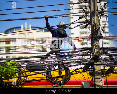 Bangkok, Bangkok, Thailandia. Il 30 maggio 2015. Un lavoratore per un locale di utilità elettriche stringhe di linee di alimentazione a piedi lungo delle linee elettriche esistenti lungo Ekkamai Soi 63 in Bangkok. La maggior parte dell'elettricità consumata in Bangkok è generato in Laos e Myanmar. Nel 2013, il Metropolitan Bangkok Regione consumato circa il quaranta per cento della Thailandia del energia anche se il BMR è solo 1,5 per cento del territorio del paese e circa il 22 per cento della sua popolazione. Credit: Jack Kurtz/ZUMA filo/Alamy Live News Foto Stock