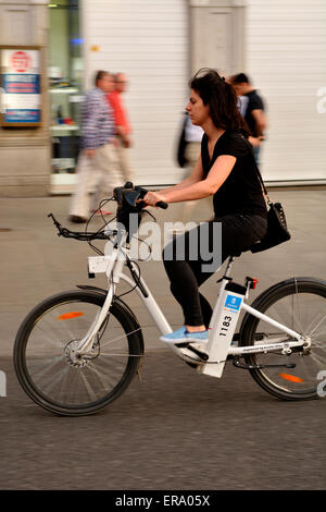 La donna a cavallo di un public shared BiciMad noleggio bicicletta elettrica a Madrid, Spagna Foto Stock