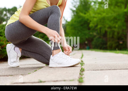 Allacciatura donna le sue scarpe in posizione di parcheggio Foto Stock