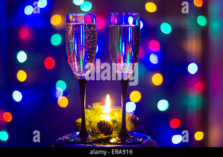 Bicchieri di champagne e una candela con sfondo colorato Foto Stock