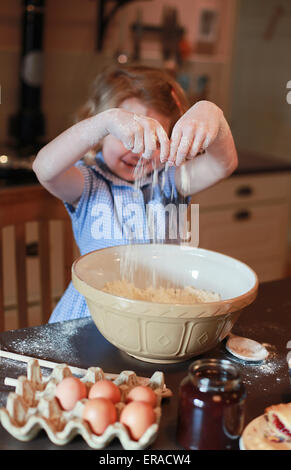 Bella bionda ragazza dai capelli miscelando gli ingredienti in un recipiente Foto Stock