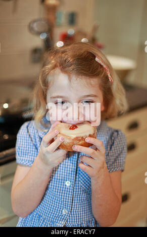 Bella bionda dai capelli bambina di mangiare una torta con la ciliegina sulla torta Foto Stock