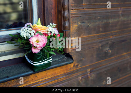 Disposizione dei fiori sul davanzale di una capanna in legno Foto Stock