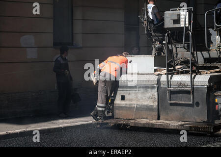 San Pietroburgo, Russia - 30 Maggio 2015: uomini al lavoro, strada urbana in costruzione, operatore lavora su lastricatore macchina Foto Stock