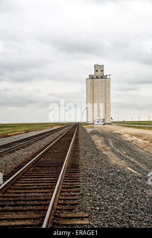 Silos (ascensore) nella distanza nella Panhandle del nord Texas. Situato alla fine della lunga strada deserta e via treno. Foto Stock