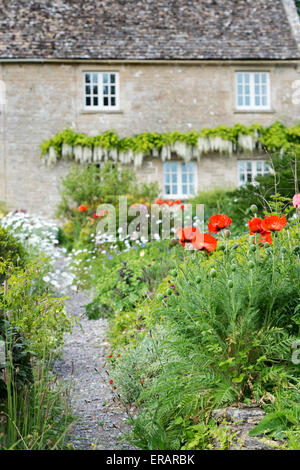 Giardino fiorito e il percorso nella parte anteriore di un cottage in Ablington. Cotswolds, Gloucestershire, Inghilterra Foto Stock