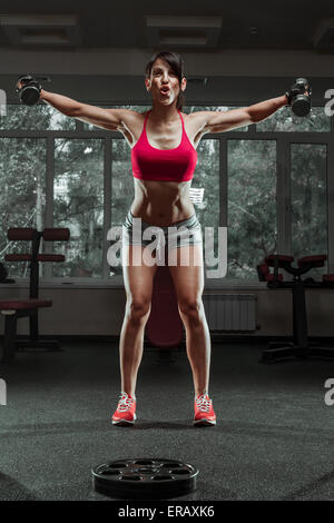 Ragazza sportiva fare esercizio con manubri in palestra Foto Stock