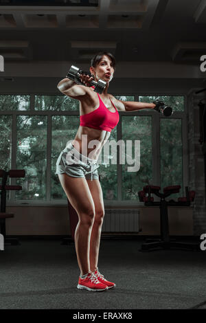 Ragazza sportiva fare esercizio con manubri in palestra Foto Stock