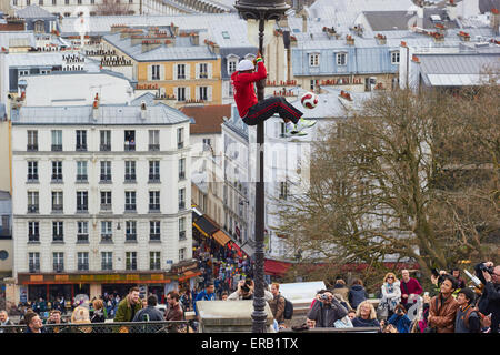 Street performer bilanciamento di un calcio di filatura durante la salita fino a via la luce guardato da turisti Montmartre Parigi Francia Foto Stock