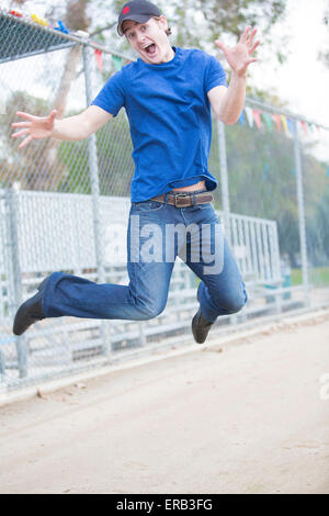 Giovane uomo saltando su un campo sportivo Foto Stock