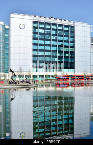 Gli uffici del fornitore di data center Global Switch riflettono in acque paesaggistiche caratterizzano le bancarelle degli autobus rossi di Londra le soleggiate Tower Hamlets East London England UK Foto Stock