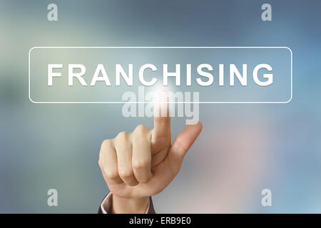 Business mano spingendo il pulsante di franchising su sfondo sfocato Foto Stock