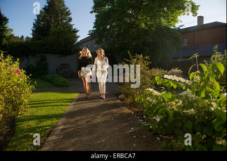 Una madre e figlia a piedi verso la telecamera in una bella luce della sera Foto Stock