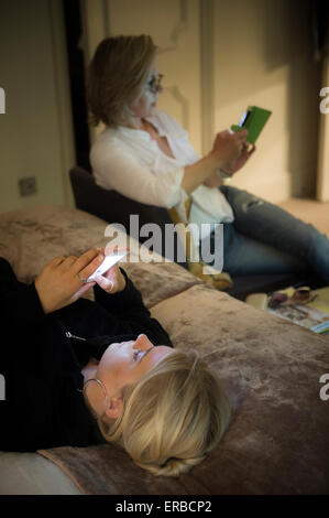 I membri della famiglia godendo di un tablet e smart phone Foto Stock