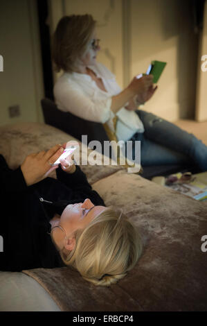I membri della famiglia godendo di un tablet e smart phone Foto Stock