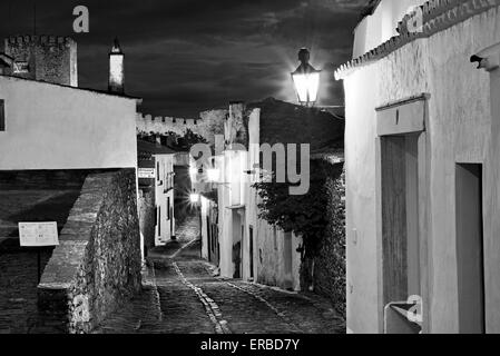 Portogallo Alentejo: orologio notturno illuminato vicolo nel borgo medievale di Monsaraz Foto Stock