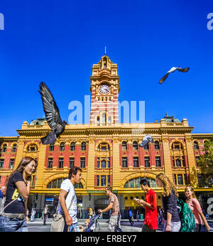 Pedoni che attraversano road, Elizabeth e la Flinders Street intersezione. Iconico Melbourne stazione ferroviaria in background Foto Stock