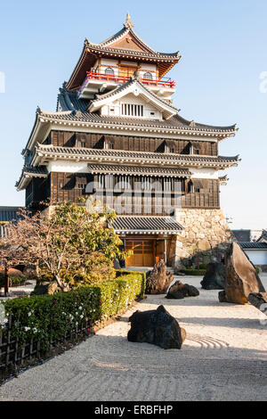 Giappone, Nagoya, ricostruito castello Kiyosu, con un castello in stile Borogata tenere il sole contro cielo blu chiaro. In primo piano un giardino in pietra giapponese. Foto Stock