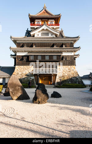 Giappone, Nagoya, ricostruito castello Kiyosu, con un castello in stile Borogata tenere il sole contro cielo blu chiaro. In primo piano un giardino in pietra giapponese. Foto Stock