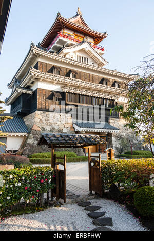 Giappone, Nagoya, ricostruito castello Kiyosu, con un castello in stile Borogata tenere il sole contro cielo blu chiaro. In primo piano un giardino in pietra giapponese. Foto Stock