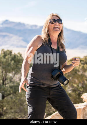 Una femmina di fotografo a ridere dopo che lo compongono una montagna. Foto Stock