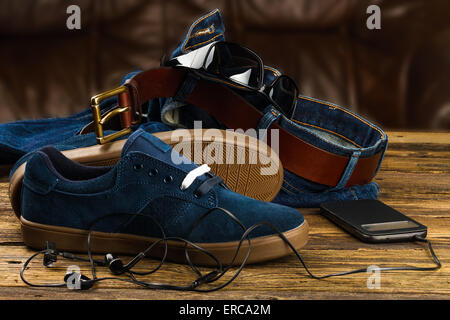 Blu scuro scarpe da uomo, jeans, lo smartphone e gli accessori su sfondo di legno Foto Stock