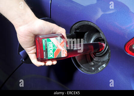 Versando detergente per sistema di alimentazione carburante nel serbatoio di un automobile Foto Stock