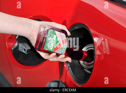 Versando detergente per sistema di alimentazione carburante nel serbatoio di un automobile Foto Stock