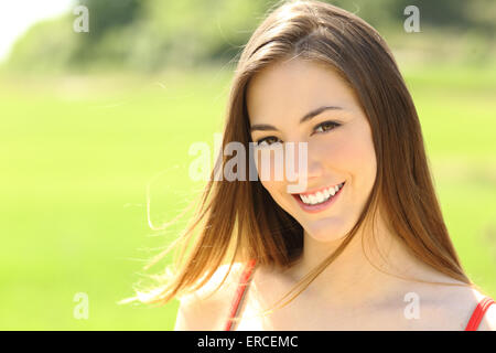 Candida donna con denti perfetti e sorriso cercando voi con il vento muovendo i suoi capelli Foto Stock