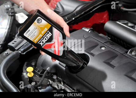 Versando un additivo olio nel motore di una macchina a smettere di fumare Foto Stock