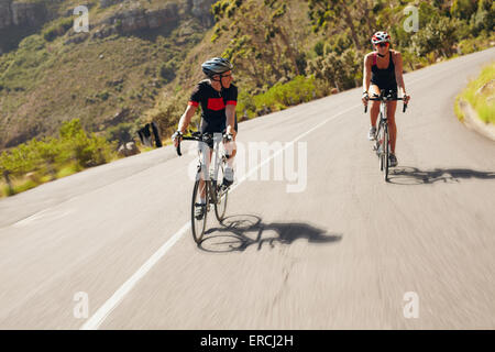 Due ciclista la pratica per la gara di triathlon. Triatleti praticare ciclismo su strada di campagna. Uomo e donna Bicicletta Equitazione su open Foto Stock