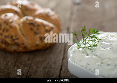 Ciotola di formaggio fresco in salsa di sfondo di legno con un bagel in background Foto Stock