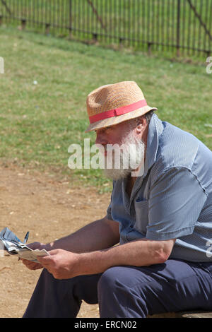 Uomo di mezza età facendo un cruciverba su una panchina nel parco, England, Regno Unito Foto Stock