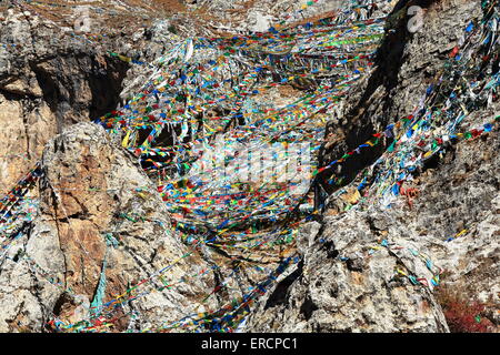 Sfilacciati bandiere da preghiera buddista appeso sul pendio di montagna sopra il Drak Yerpa monastero-complesso di grotte. Il Tibet. Foto Stock