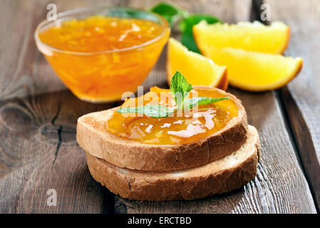 Pane e orange marmellata fatta in casa sul tavolo di legno, vista ravvicinata Foto Stock