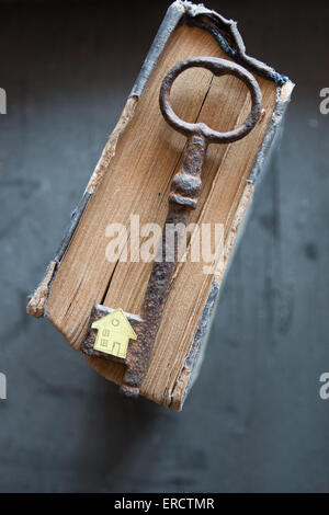Chiave di casa. Chiave vintage, vecchio libro e casa di carta. Foto Stock