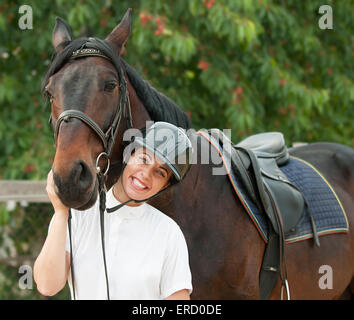 Allegro jockey giovane donna con cavallo di razza in esterno Foto Stock