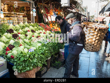 Un portiere e le chat in un vegetale in stallo Kadikoy street market, Istanbul, Turchia. Foto Stock