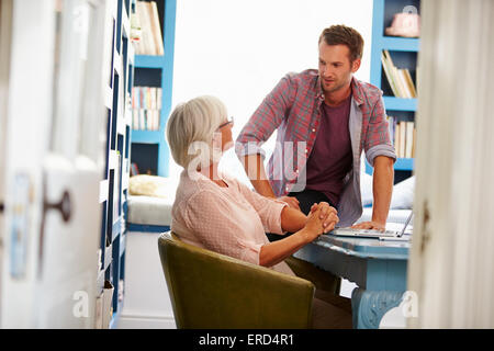 Figlio dando Senior genitore consulenza finanziaria In Home Office Foto Stock